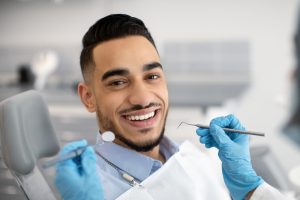 dentist holding dental tools near smiling patient